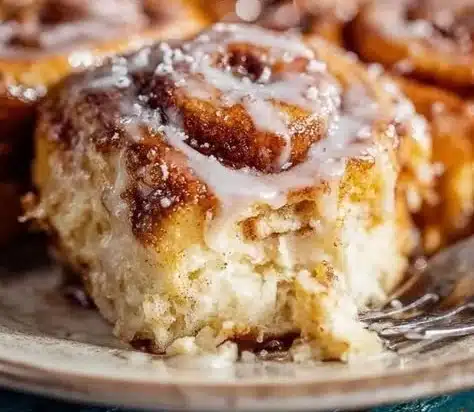Freshly baked homemade cinnamon rolls with icing on a wooden table