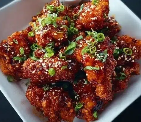 Korean Fried Chicken 4 Plate of crispy Korean Fried Chicken with dipping sauce and garnish.